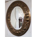 An early 20th century oval brass framed bevelled glass wall mirror with embossed fruit on the vine