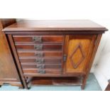 An early 20th century arts and crafts music cabinet with six drawers alongside single cabinet