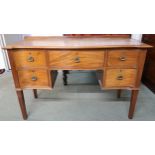 A 20th century mahogany serpentine front desk with central drawer flanked by two drawers on either