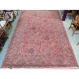 A large machine woven terracotta ground rug with allover floral/foliate design with flower head
