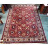 A red ground Persian style rug with allover flowerhead design and flowerhead border, 352cm long x