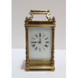 A French brass and glass carriage clock with column supports and galleried detail, with travel