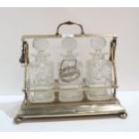 An EPNS tantalus with three cut glass decanters, one with a silver label Helpyersel Condition