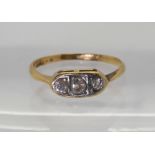 An 18ct gold three stone diamond ring set with two old cuts and a modern brilliant cut, with an