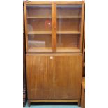 A mid 20th century teak bookcase with pair of glazed doors over pair of cabinet doors on shaped