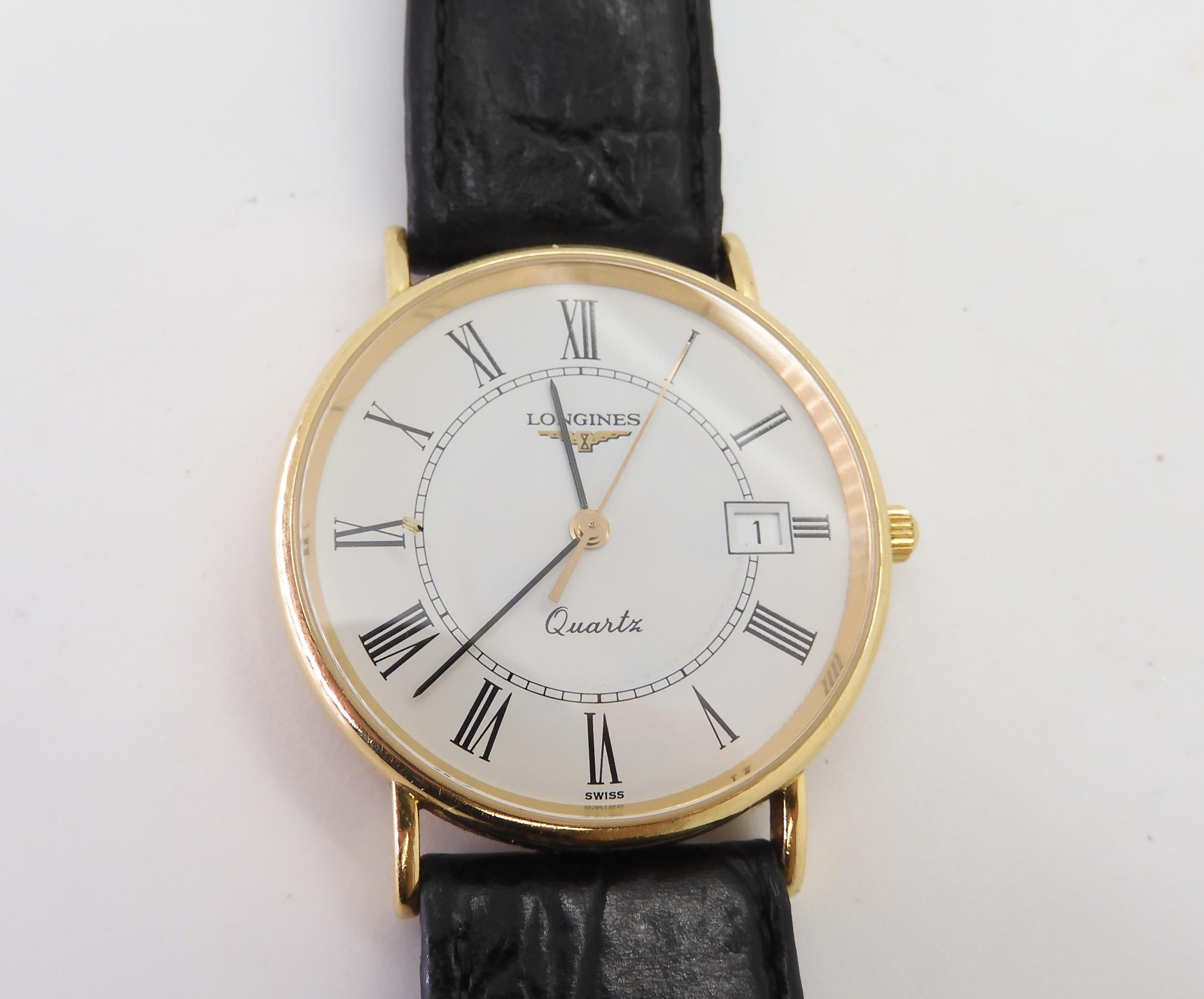 An 18k gold Longines Quartz watch, with a black leather strap, with gold plated Longines buckle,