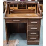 An early 20th century oak tambour top desk with fitted interior over single long drawer alongside