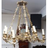 An early 20th century gilt Rococo revival multibranch chandelier with brass hanging chains cast in a