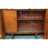 A mid 20th century teak bookcase with cabinet door alongside sliding glass doors on shaped supports,