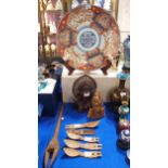 A large Imari charger decorated with cranes, two carved wooden heads, tribal carved wooden spoons