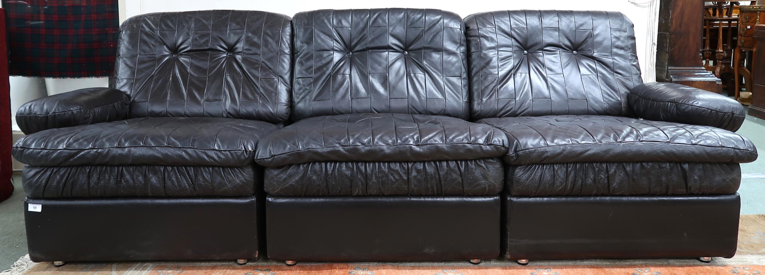 A mid 20th century after Tetrad sectional three seater sofa with black patchwork leather upholstery,