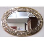 An early 20th century British brass framed oval wall mirror with frame embossed with flowerheads and