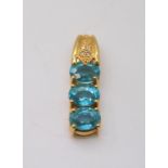 An 18ct gold pendant set with three swimming pool blue apartites and diamond accents, length 3cm,
