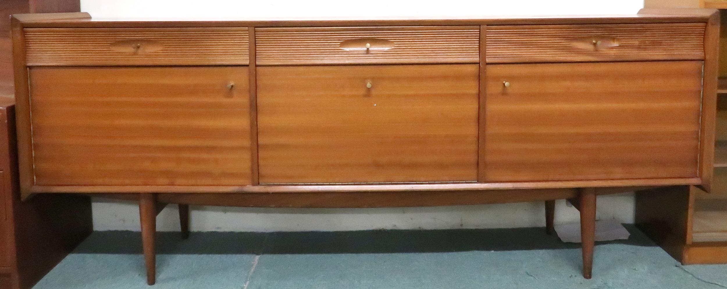 A mid 20th century teak sideboard with three drawers over central fall front compartment flanked