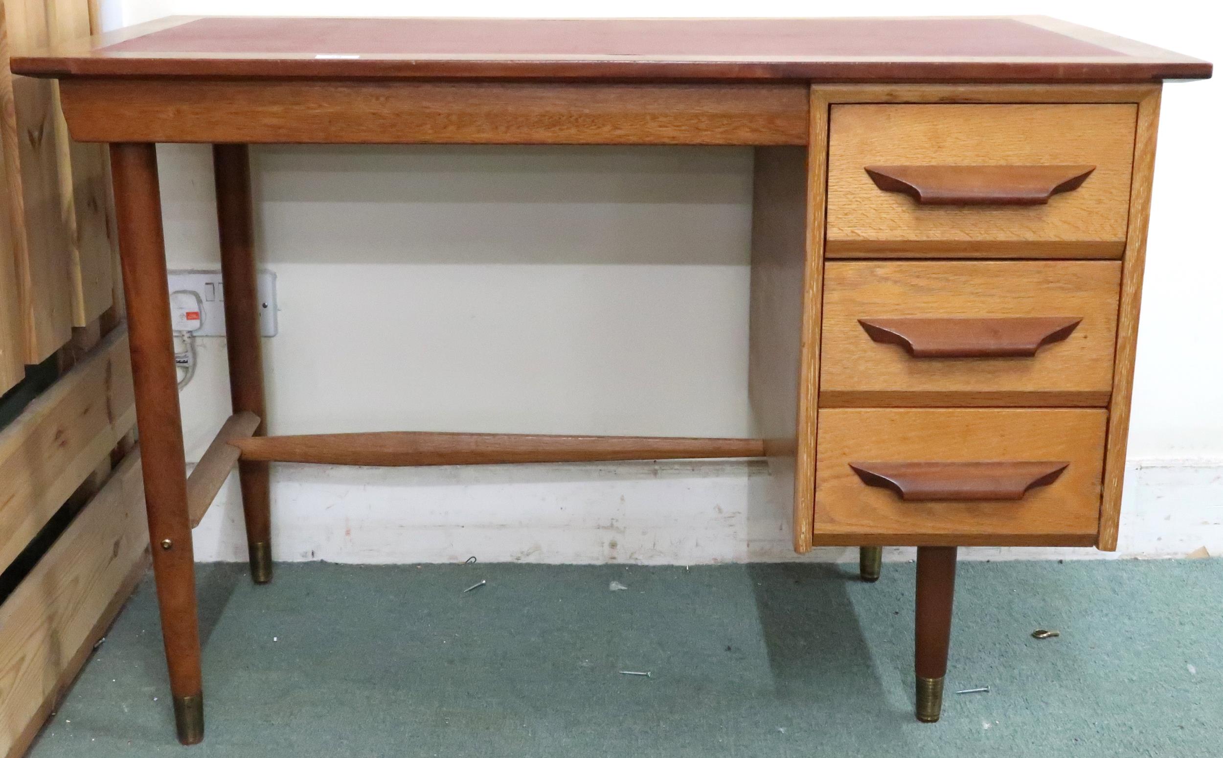 A mid 20th century teak desk with red vinyl skiver over bank of three drawers on tapering