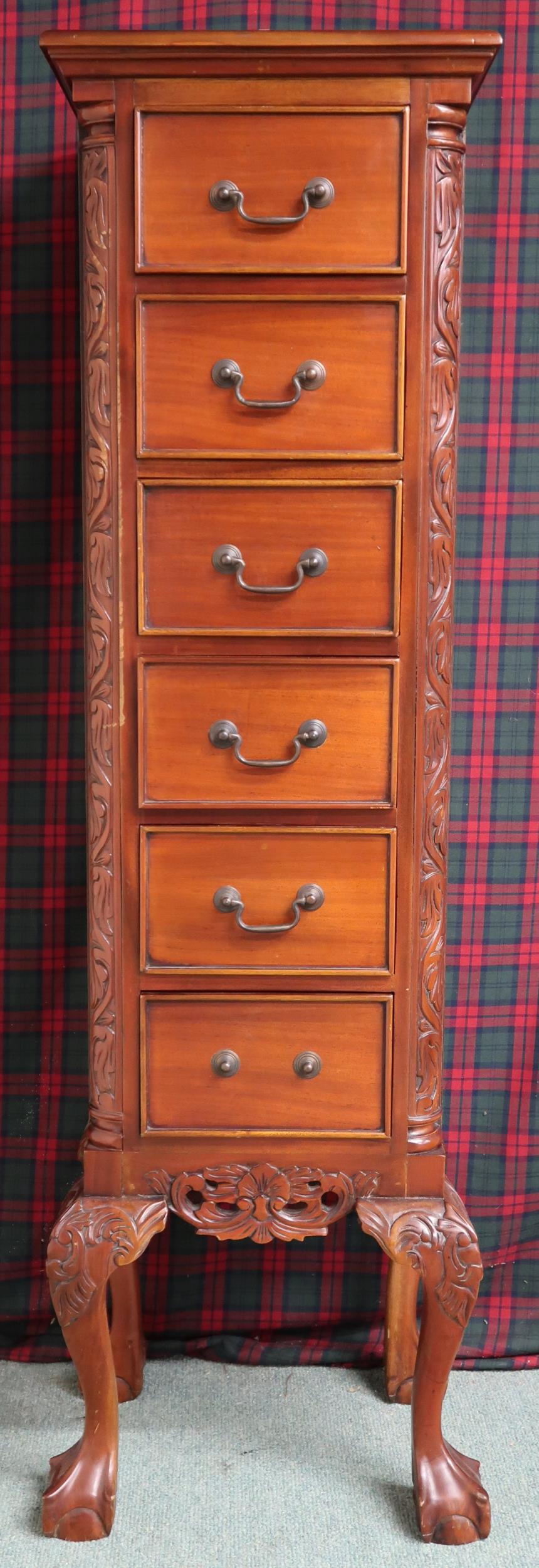 A 20th century mahogany tall boy chest with six drawers flanked by carved reliefs on ball and claw