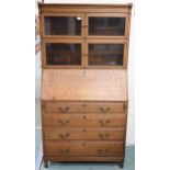 An early 20th century oak bureau bookcase with dual sectional bookcase top with glazed doors over