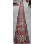 A large pink ground runner with repeating medallions with multicolour border, 1250cm long x 58cm