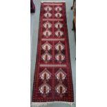 A red ground Balouch runner with geometric panels and multicoloured borders, 295cm long x 82cm