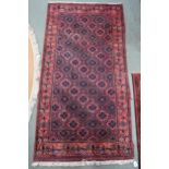 A pink ground balouch rug with allover flower head pattern ground and geometric floral border, 179cm