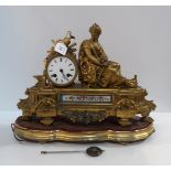 A gilt metal mantle clock with drum head dial, mounted with a classical style maiden and swags of