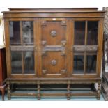 A 20th century oak Jacobean style glazed bookcase with central panel door with carved rondels