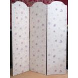 A contemporary three panelled room divider upholstered in floral cream fabric with studded edges,