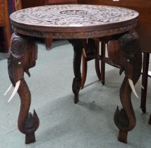 An early 20th century hardwood "elephant" table with carved circular top on carved supports in the