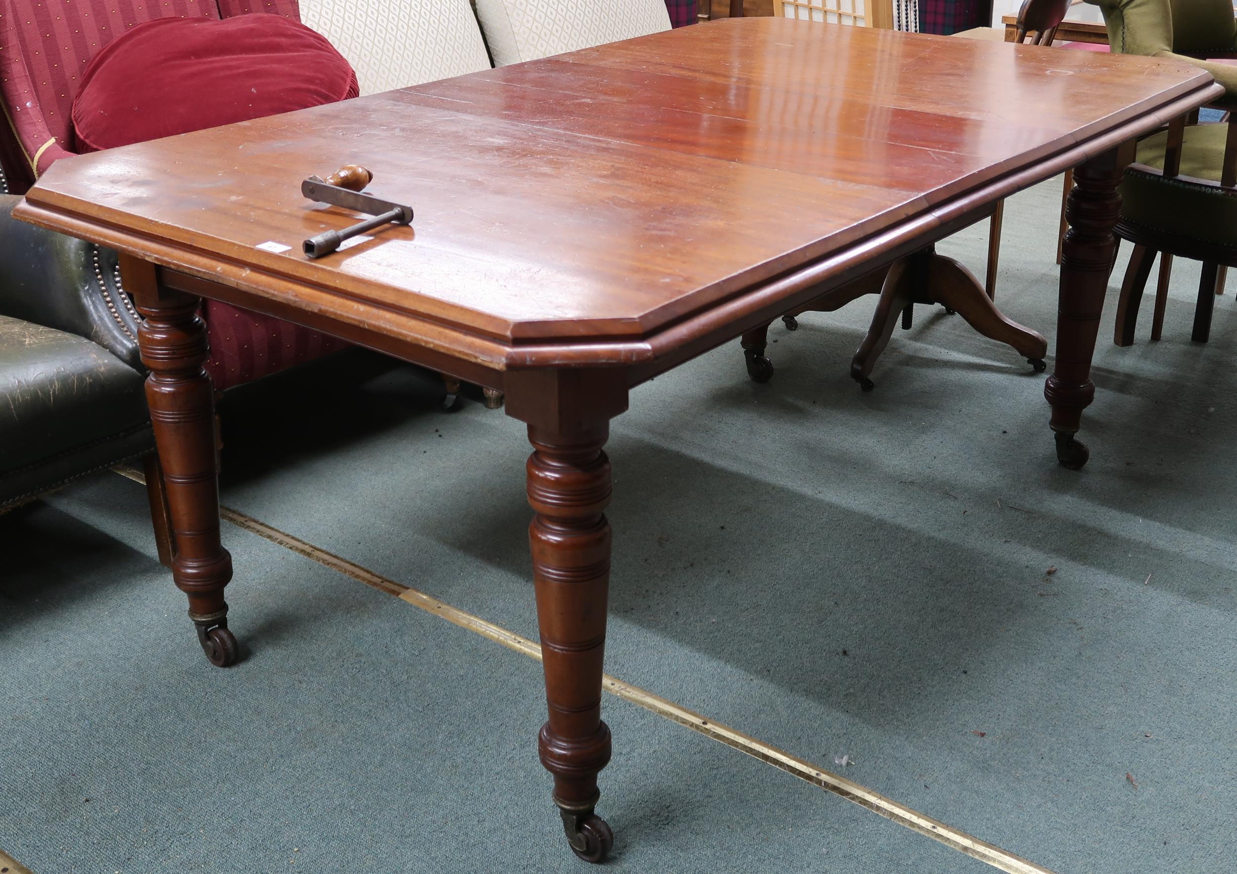 A Victorian mahogany wind out extending dining table on turned supports terminating in ceramic