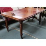 A Victorian mahogany wind out extending dining table on turned supports terminating in ceramic