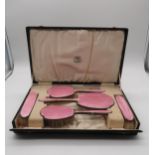 Hamilton & Inches; A cased five piece pink guilloche enamel dressing table set, comprising two