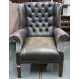An early 20th century Chesterfield style green leather button back upholstered wing back armchair on