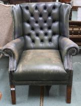 An early 20th century Chesterfield style green leather button back upholstered wing back armchair on