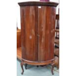 A 20th century mahogany bow front corner cabinet with pair of cabinet doors on cabriole feet,
