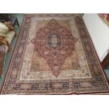 A red floral patterned ground Kashmiri rug with dark blue central medallion, beige spandrels and