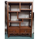 A 20th century Oriental hardwood open bookcase with four asymmetrical shelves over pair of drawers