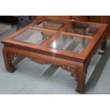 A large contemporary Oriental style coffee table with bevelled glass inset top on shaped supports