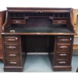 An early 20th century stained oak roll top desk with tambour topped writing compartment concealing