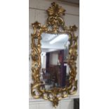 A 20th century gilt framed Rococo style wall mirror with scrolled foliate frame, 122cm high x 56cm