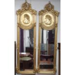 A pair of 20th century gilt Rococo style peer mirrors with scrolled foliate surmount over oval