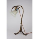 AN ARTS AND CRAFTS TABLE LAMP the gilded metal body with hammered decoration, and three leaves