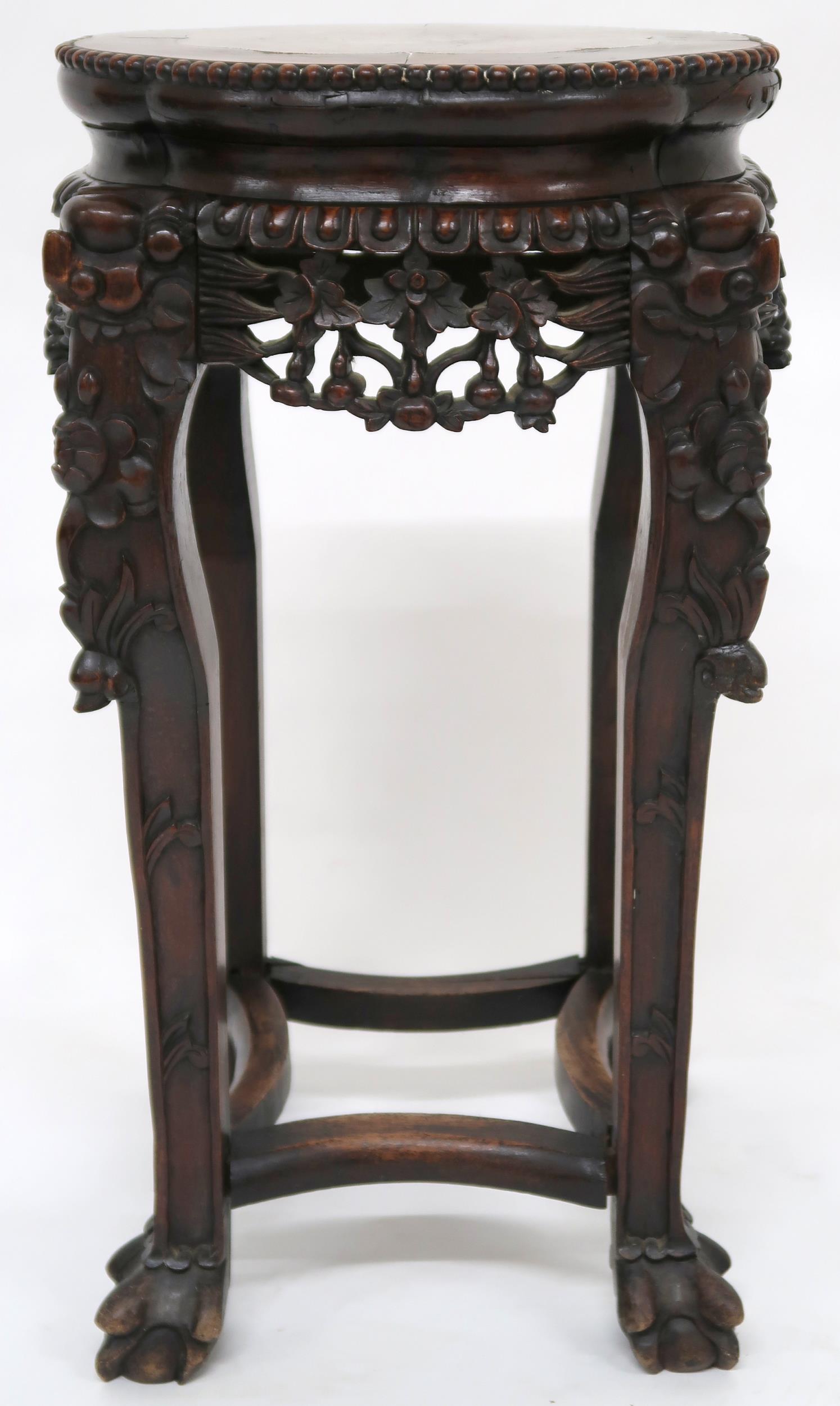 A CHINESE HARDWOOD JARDINERE STAND  with shaped top inset with pink marble over floral carved