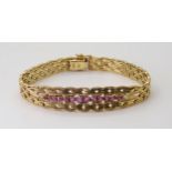 AN ITALIAN MADE 18CT GOLD BRACELET set with pink sapphires to the wavy link constructed bracelet,