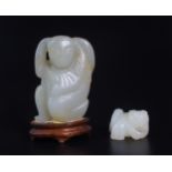 A CHINESE HARDSTONE CARVING  Kneeling with a fish on his shoulder, 5.5cm high and a hardstone