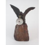A BRONZE AND STONE WATCH HOLDER modelled as an eagle perched on a rock, holding a German made