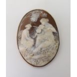 A WELL CARVED CAMEO depicting a maiden playing a violin to another. In a yellow metal pendant brooch
