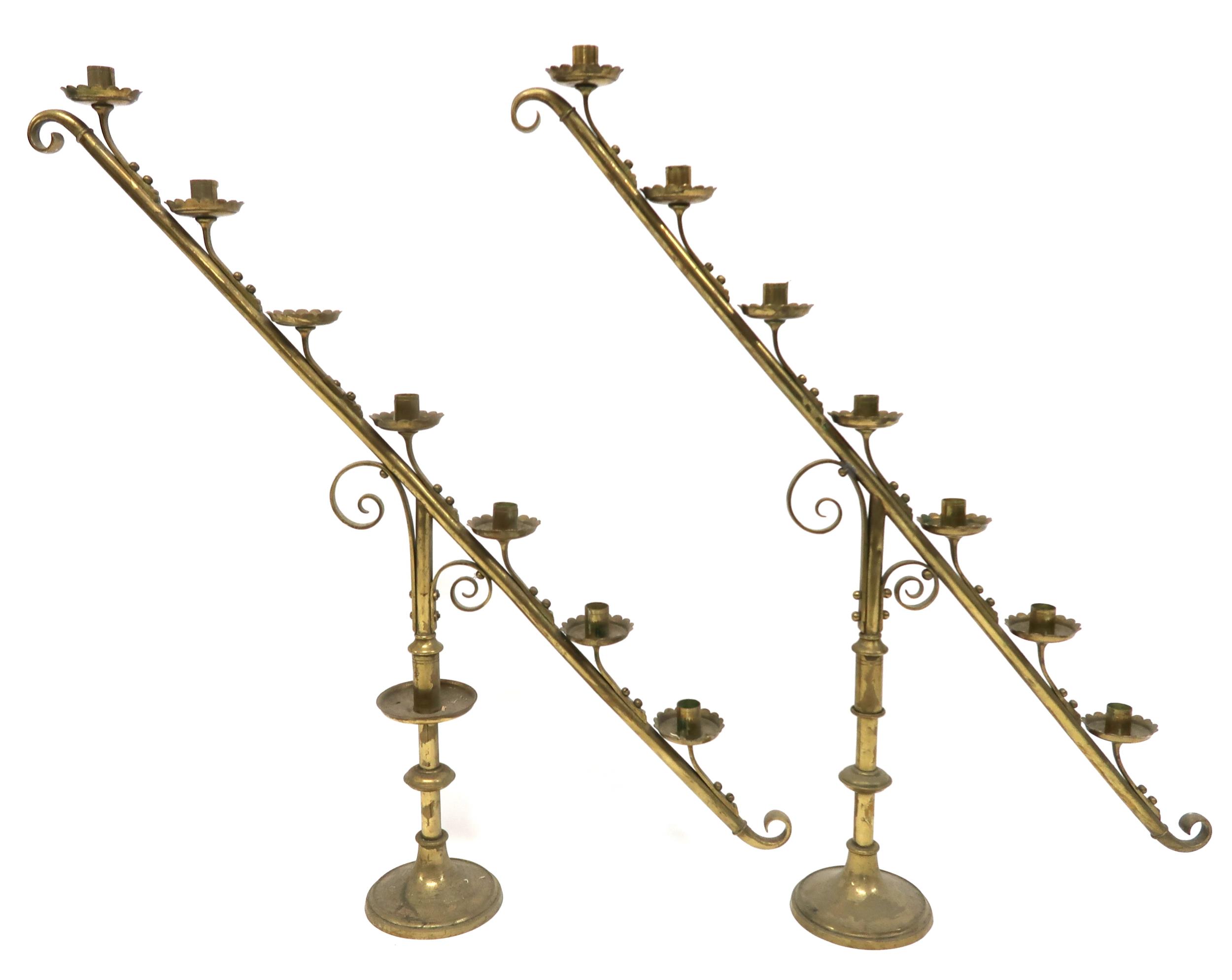 A PAIR OF 19TH CENTURY BRASS ECCLESIASTICAL SLOPED CANDELABRA each with seven candle holders with