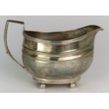 A GEORGE III SILVER CREAM JUG maker's mark rubbed, London 1806, of oval form, with two shaped bands,