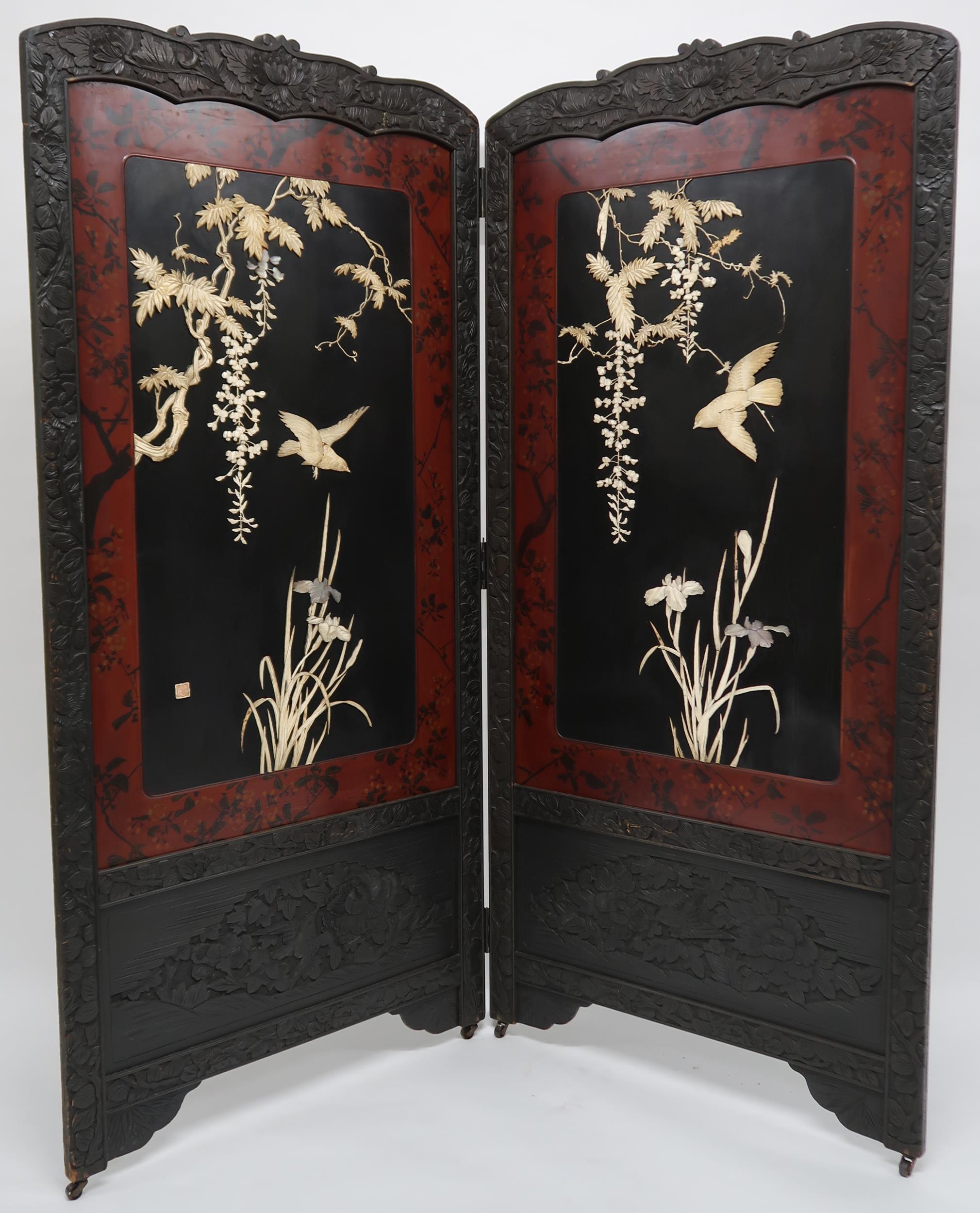 AN ORIENTAL HARDWOOD FRAMED LACQUERED TWO FOLD ROOM DIVIDER with foliate carved frame surrounding