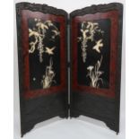 AN ORIENTAL HARDWOOD FRAMED LACQUERED TWO FOLD ROOM DIVIDER with foliate carved frame surrounding